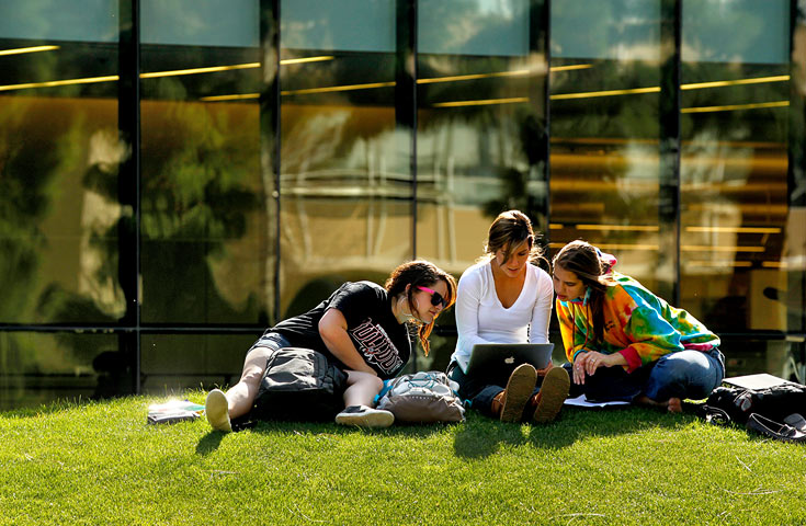 Students Sitting on Grass in Front of Library